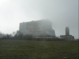 Gloomy picture of overshadowing tower with top hidden by mist