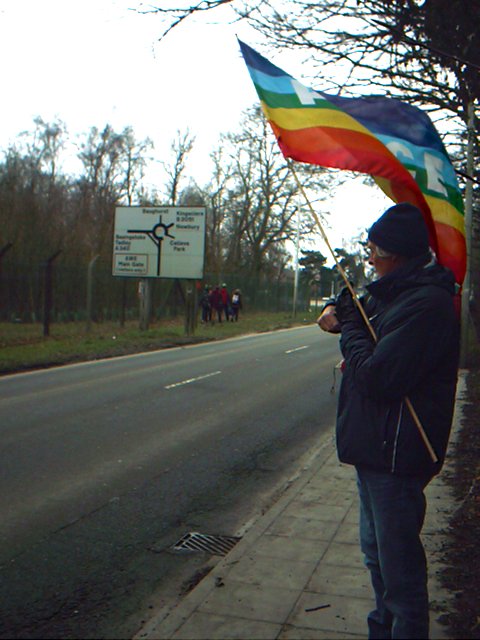Protester with rainbow flag in front of road sign